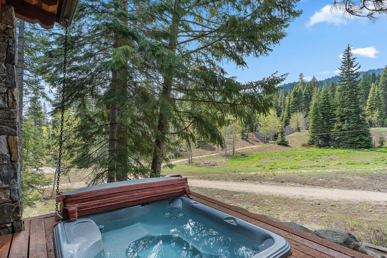 Un bain à remous sur une terrasse en bois, avec vue sur une forêt et un sentier de terre.