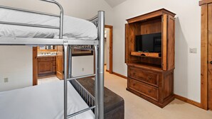 Een stapelbed met een televisiekast en een deur in een kamer.