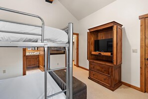 Un lit superposé avec un meuble pour la télévision et une porte dans la pièce.