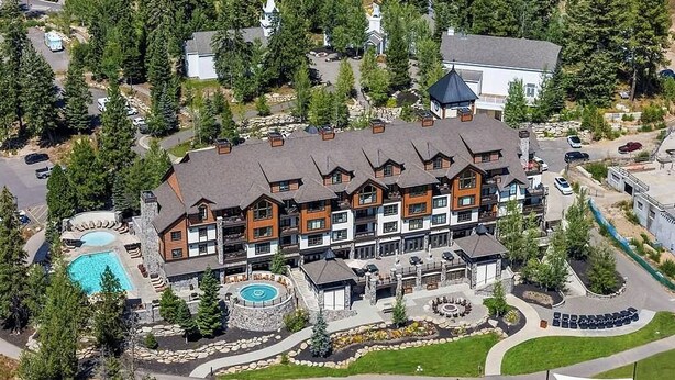 A multi-story hotel with a pool, outdoor seating, and a well-maintained garden.