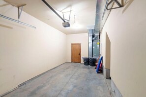 Un pasillo limpio y vacío con una puerta de madera al final, un proyector instalado en el techo y un conducto de ventilación.
