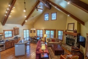 A spacious living area with a fireplace, a dining table, and a kitchen with wooden cabinets.
