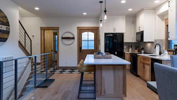 A modern kitchen with wooden cabinets, a central island, and a staircase with a metal railing.