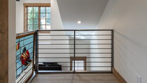 A spacious loft bedroom with a high ceiling, a large window with a view of trees, a sliding glass door, and a wooden floor. - Ideal 2 Bedroom Townhome  | Ski in/Ski Out (Tamarack)