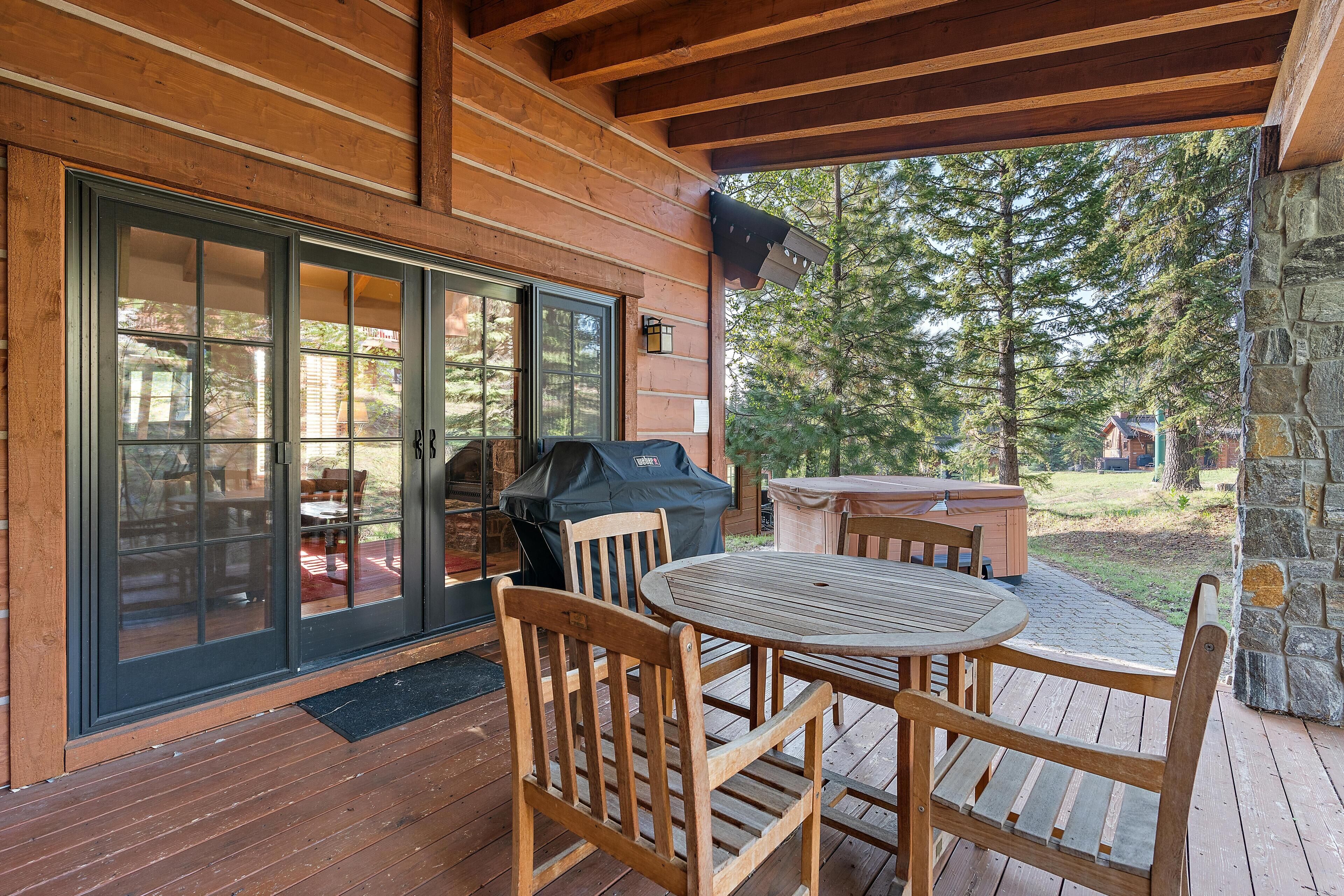 Une terrasse en bois avec une table et des chaises, un barbecue et un mur en pierre.