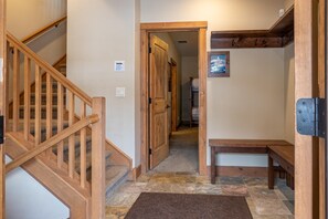 Un escalier en bois menant à un palier où se trouvent un banc et une porte.