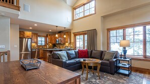 A spacious living area with a wooden dining table, a sofa, and a kitchen in the background. - Beautiful Townhome|Private Hot Tub, Ski-In/Ski-Out (Tamarack)