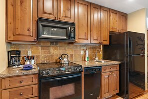 A kitchen with wooden cabinets, a microwave, stove, dishwasher, and a refrigerator. - Wonderful Cottage |Ski In/Out | Private Hot Tub (Tamarack)