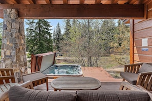 A wooden deck with a hot tub, stone wall, and wooden furniture. - Wonderful Cottage |Ski In/Out | Private Hot Tub (Tamarack)