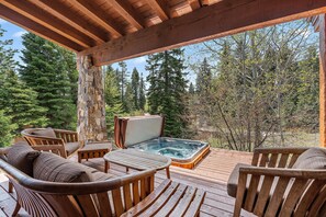 A wooden deck with a hot tub, outdoor furniture, and a view of a forest. - Wonderful Cottage |Ski In/Out | Private Hot Tub (Tamarack)