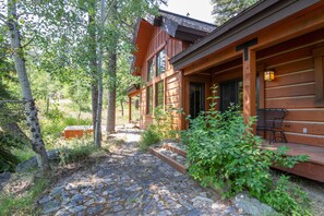 Une cabane en bois avec un chemin de pierres menant à l’entrée, entourée de verdure.
