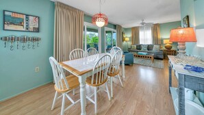 Un coin repas avec une table et des chaises en bois, un ventilateur de plafond et un luminaire suspendu.