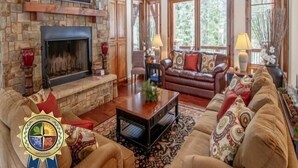 A spacious living room with a stone fireplace, wooden beams, and large windows. - Remarkable Estate Home|Wood Fireplace|Resort Views (Tamarack)