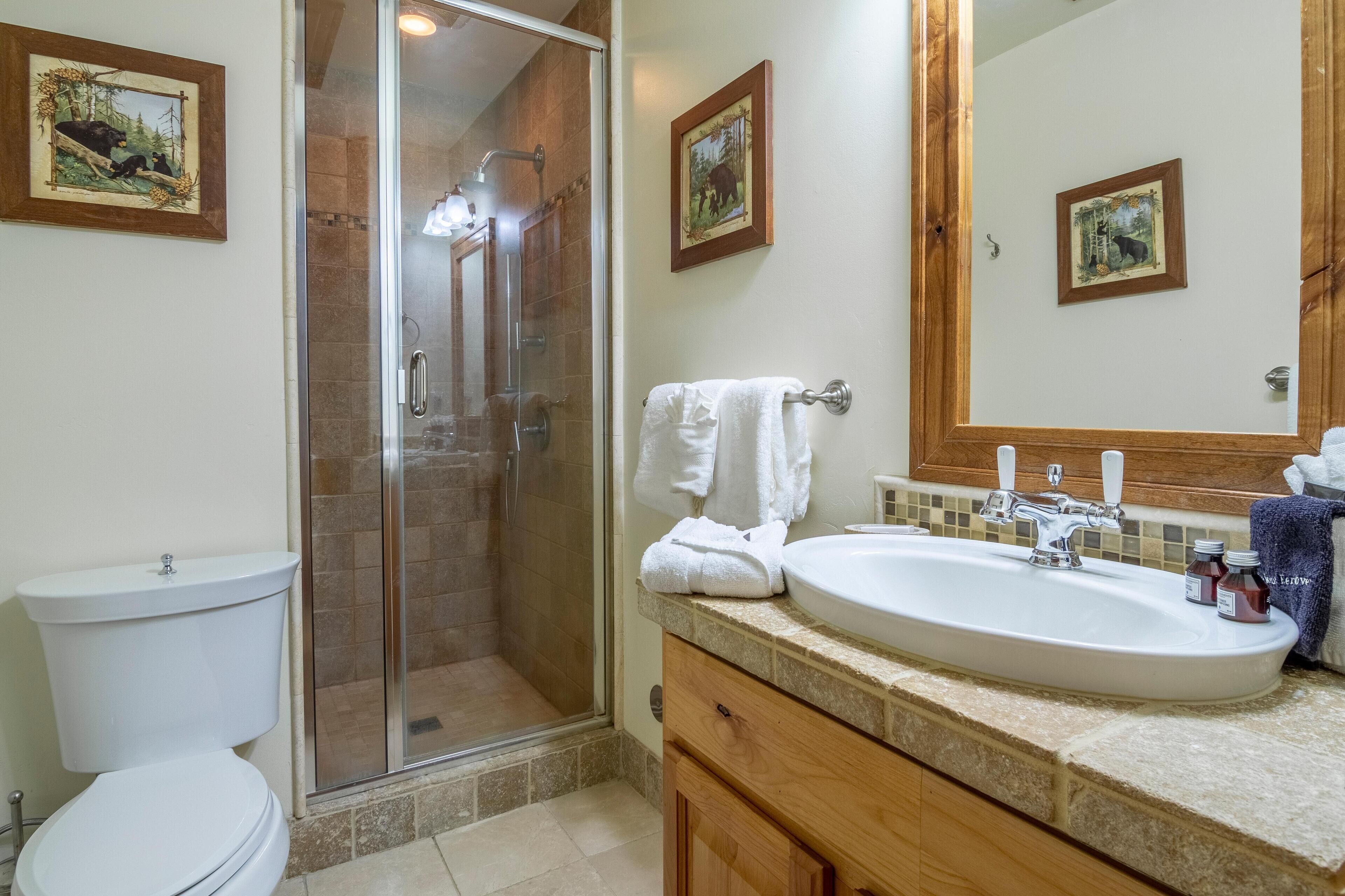 A bathroom with a glass-enclosed shower, a white sink, and a mirror above it.