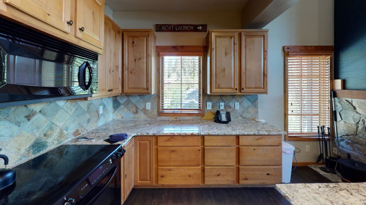 A kitchen with wooden cabinets, a granite countertop, a stove, and a sign that reads "Boat Launch".