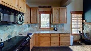 A kitchen with wooden cabinets, a granite countertop, a stove, and a sign that reads "Boat Launch".