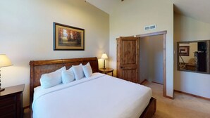 A neatly arranged bedroom with a large bed, two bedside tables with lamps, a wooden wardrobe, and a framed picture on the wall. - Beautiful Townhome|Private Hot Tub, Wood Fireplace (Tamarack)