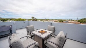 Une terrasse sur le toit, dotée d’un foyer et de quatre chaises, offrant une vue sur le paysage urbain.