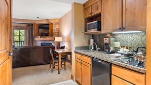A kitchen with wooden cabinets, a granite countertop, a built-in microwave, and a dishwasher. - Unique King Studio  with Jet Tub (Tamarack)