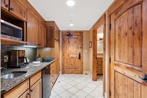 Una cocina con armarios de madera, microondas integrado y cafetera.
