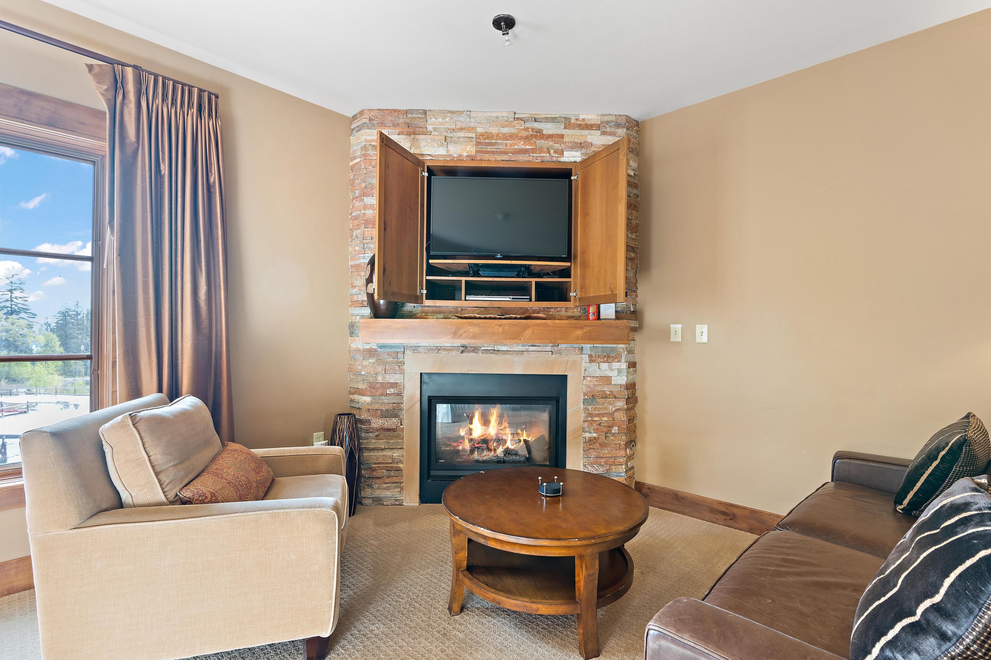 A living room with a fireplace, a flat-screen TV, and two sofas.