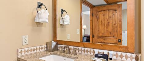 Baño con lavamanos, toallero, espejo y puerta de madera.