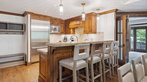 Una cocina con armarios de madera, un refrigerador de acero inoxidable, un microondas empotrado y una isla grande con taburetes de bar.