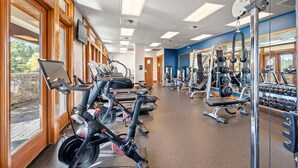 Ein Fitnessstudio mit Trainingsgeräten, großen Fenstern und Blick ins Freie.