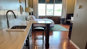 A kitchen with a pizza box, a sink, and a dining area with a table and chairs.
