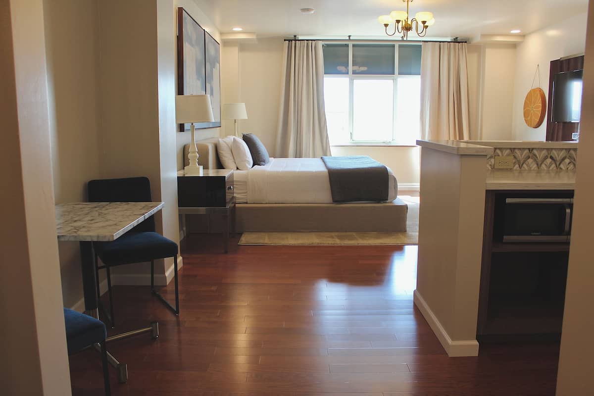 A hotel room with a bed, a desk with a chair, a TV, and a microwave.