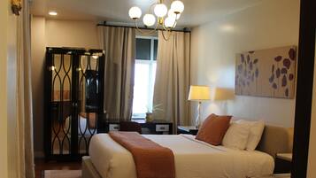 A bedroom with a large bed, a nightstand, a lamp, a painting, and a wardrobe.