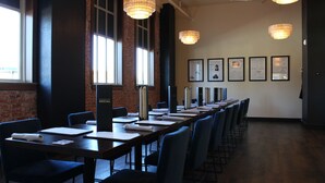 A conference room with long tables, chairs, and hanging pendant lights.