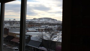 A view through a window of a town with buildings and a snow-covered hill in the background.