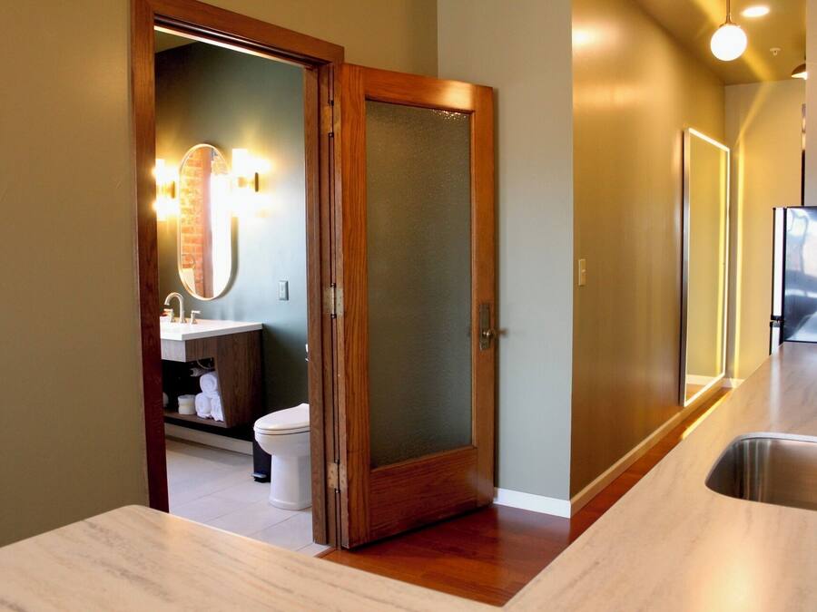 Un baño moderno con puerta de madera, un lavabo y un espejo.