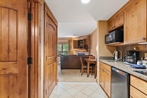 Una cocina con armarios de madera, un comedor con mesa y sillas, y un microondas empotrado.