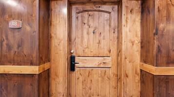 Una puerta de madera con una placa de número, un ojo de cerradura y un pomo.