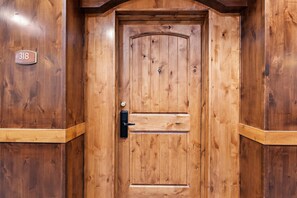 Una puerta de madera con una placa de número, un ojo de cerradura y un pomo.