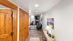 Un pasillo con puertas de madera, chimenea, sofá y televisor.