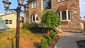 A stone house with a well-maintained lawn, a large tree, and a security camera. - Comfortable stay in a large home on the shores of Lake Erie (Dunnville)