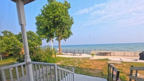 A covered outdoor area with a view of the ocean, a wooden deck, and a picnic table. - Comfortable stay in a large home on the shores of Lake Erie (Dunnville)
