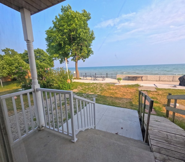 A covered outdoor area with a view of the ocean, a wooden deck, and a picnic table.