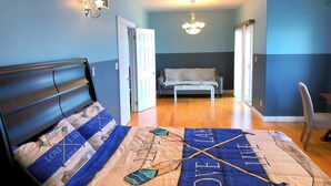 A bedroom with a bed, a nightstand, a chair, a sofa, and a hallway leading to another room. - Comfortable stay in a large home on the shores of Lake Erie (Dunnville)