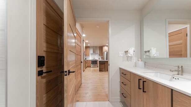 A modern kitchen with wooden cabinets, a white countertop, and a large mirror.
