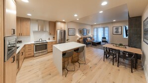 A modern kitchen with wooden cabinets, stainless steel appliances, and a central island with bar stools.