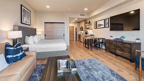 A modern hotel room with a bed, a sofa, a coffee table, and a dining area with a table and chairs. - Gorgeous Condo|Juliette Balcony|Mountain & Village Views (Tamarack)