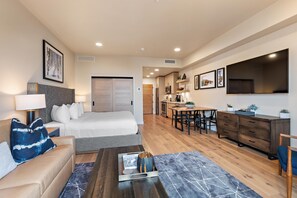 Une chambre d’hôtel moderne comprenant un lit, un canapé, une table basse et un coin repas avec une table et des chaises.