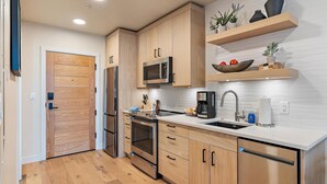 A modern kitchen with wooden cabinets, stainless steel appliances, and a white countertop. - Gorgeous Condo|Juliette Balcony|Mountain & Village Views (Tamarack)