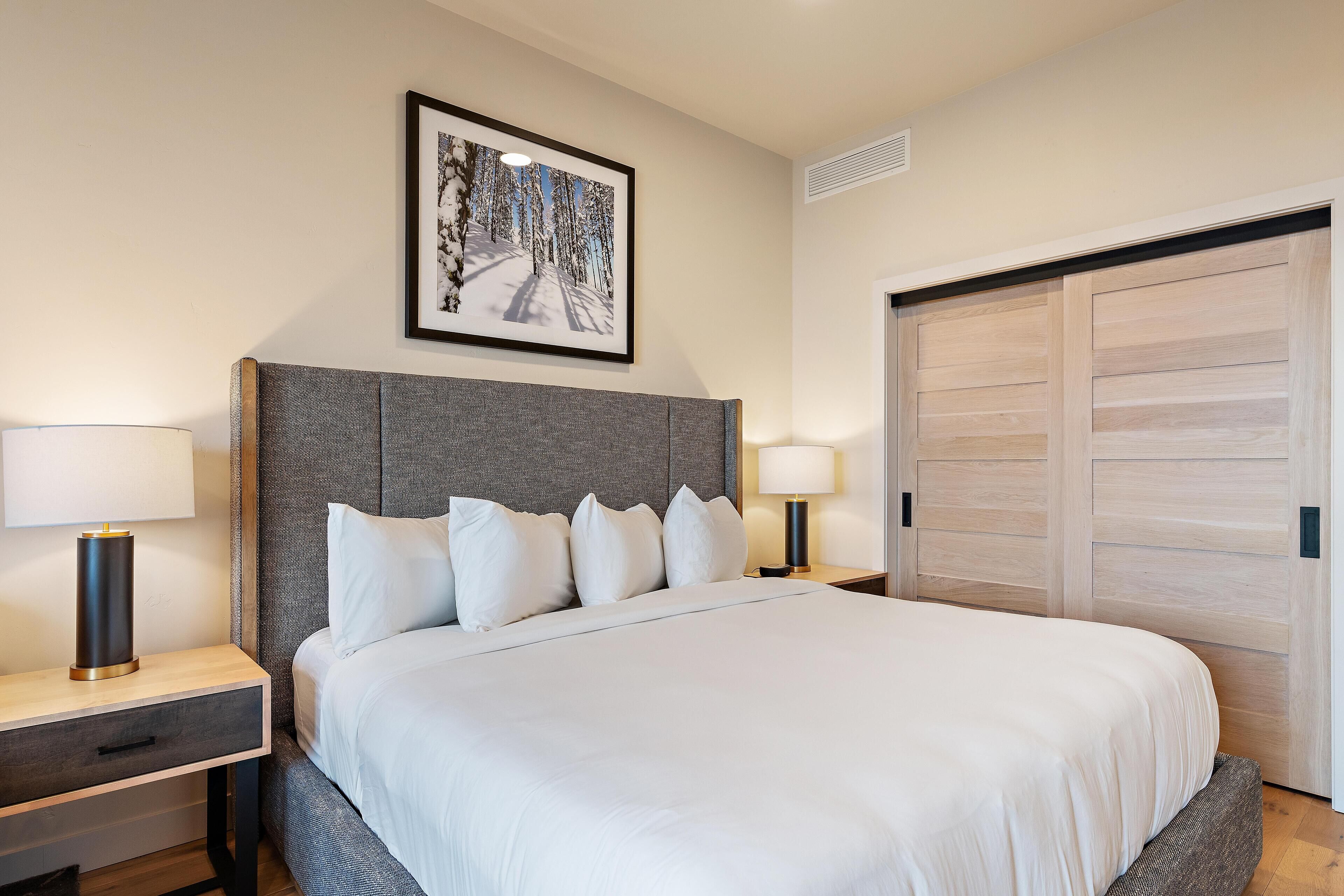 Een netjes ingerichte hotelkamer met een groot bed, twee nachtkastjes en een ingelijst schilderij aan de muur.