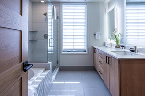 A modern bathroom with a glass-enclosed shower, a bathtub, and a vanity with a sink and mirror.