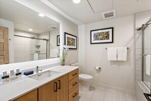 Un baño moderno con un espejo grande, una ducha y un inodoro.